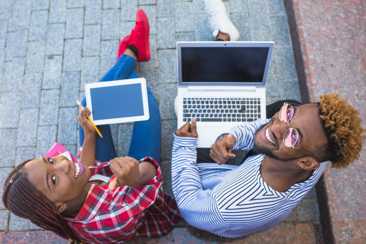 Students learning together outdoors with laptops